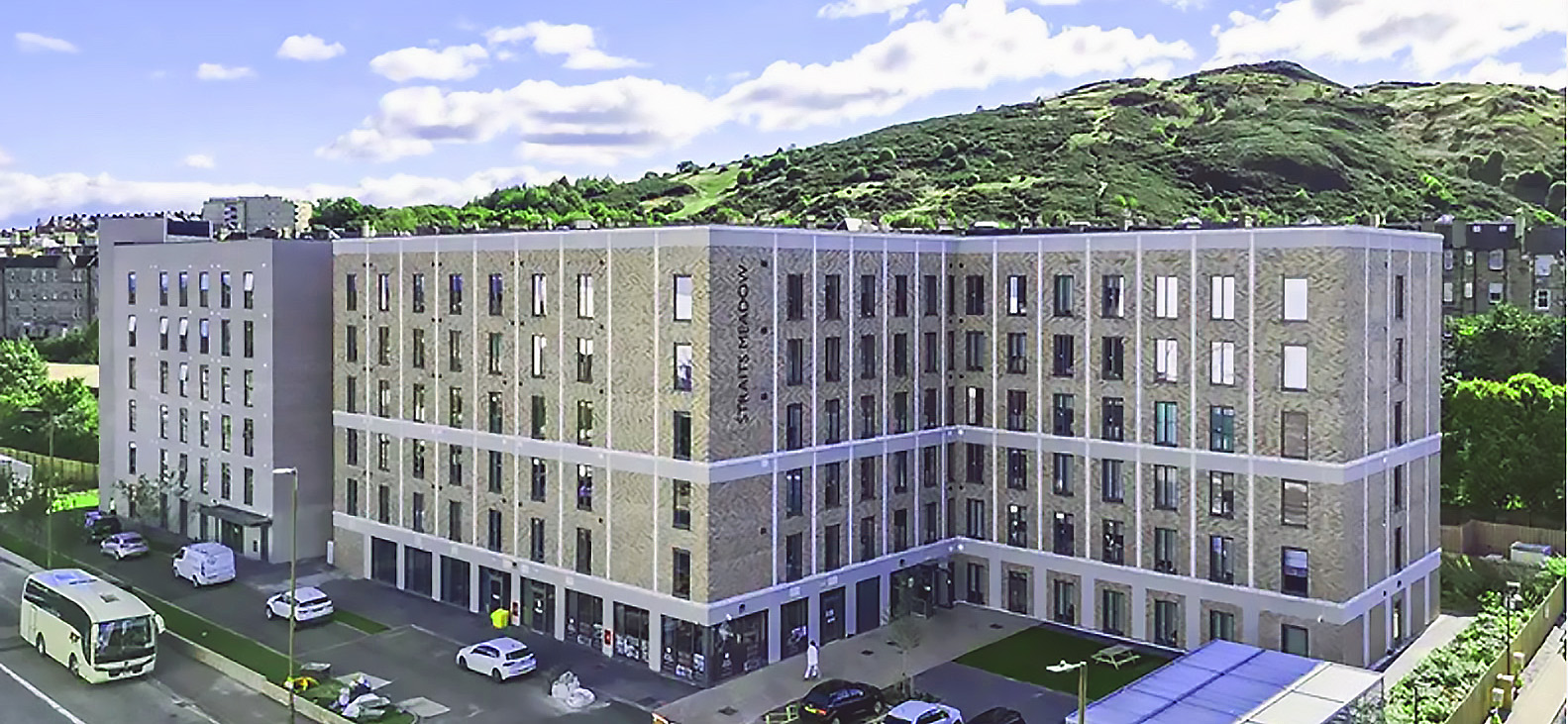 A residential building with many windows and a hill in the background